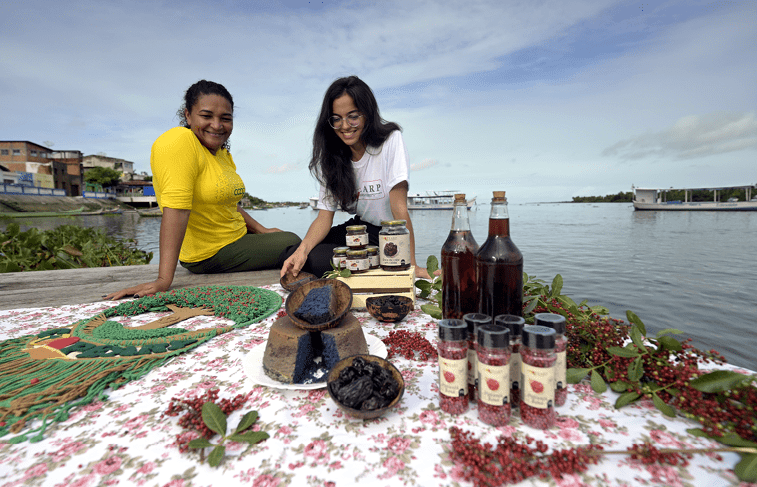 Piacabucu_AL, 16 de junho de 2025 OCB - COOPERATIVAS DO BRASIL: RETRATOS DE UM MUNDO MELHOR  COOPEARP (Cooperativa Ecoagroextrativista Aroeira de Piacabucu), reflorestamento e beneficiamento de plantas alimenticias silvestres da regiao da foz do rio Sao Francisco.  Rita Paula dos Santos Ferreira (e) e lasmim Silva Oliveira  (d) com produtos da COOPEARP as margens do Rio Sao Francisco.  Imagem: Douglas Magno / NITRO