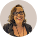 Pessoa adulta sorridente com cabelo ondulado curto, usando culos de arma  o preta, brincos geom tricos e blazer preto sobre roupa escura.  Description generated by AI