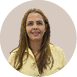 Pessoa adulta com cabelo longo e liso usando camisa amarela clara e sorrindo com aparelho nos dentes em fundo neutro circular. Description generated by AI
