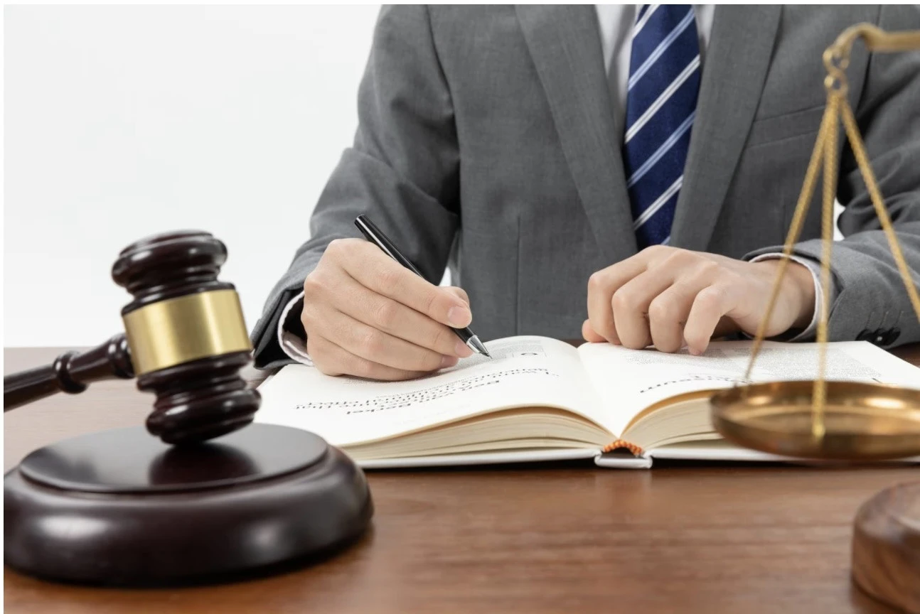  Homem faz anotações próximo de balança da justiça e malhete